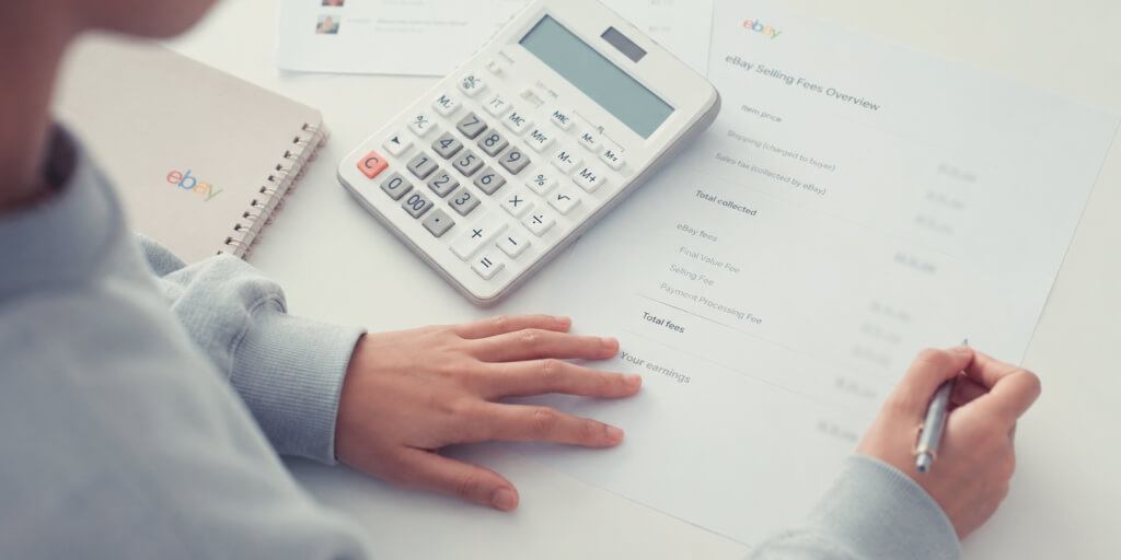 An eBay seller sitting at a table calculating eBay fees.